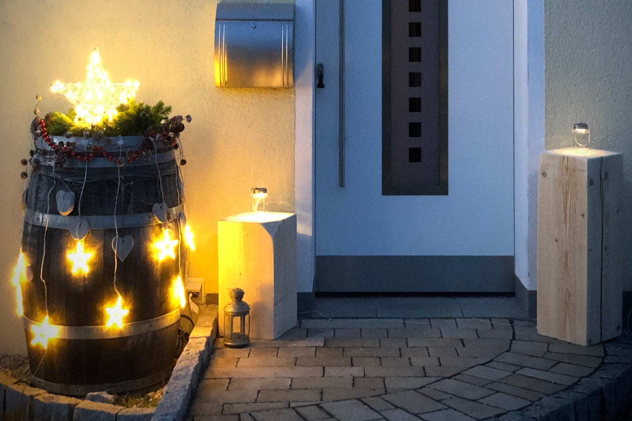 Weihnachtlich dekoriertes Weinfass mit Beleuchtung vor Hauseingang