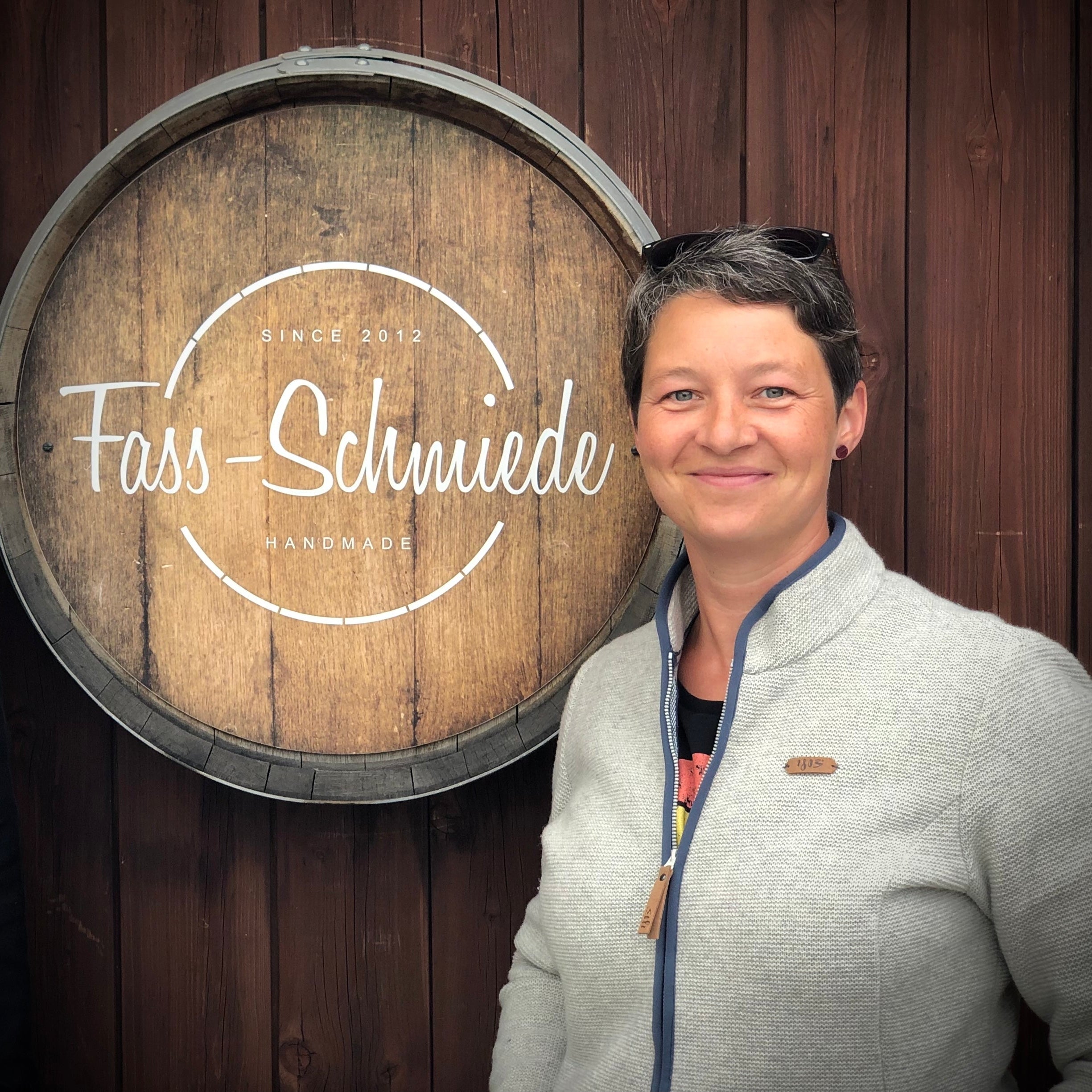 Jana vor einem Weinfass mit Logo der Fass-Schmiede