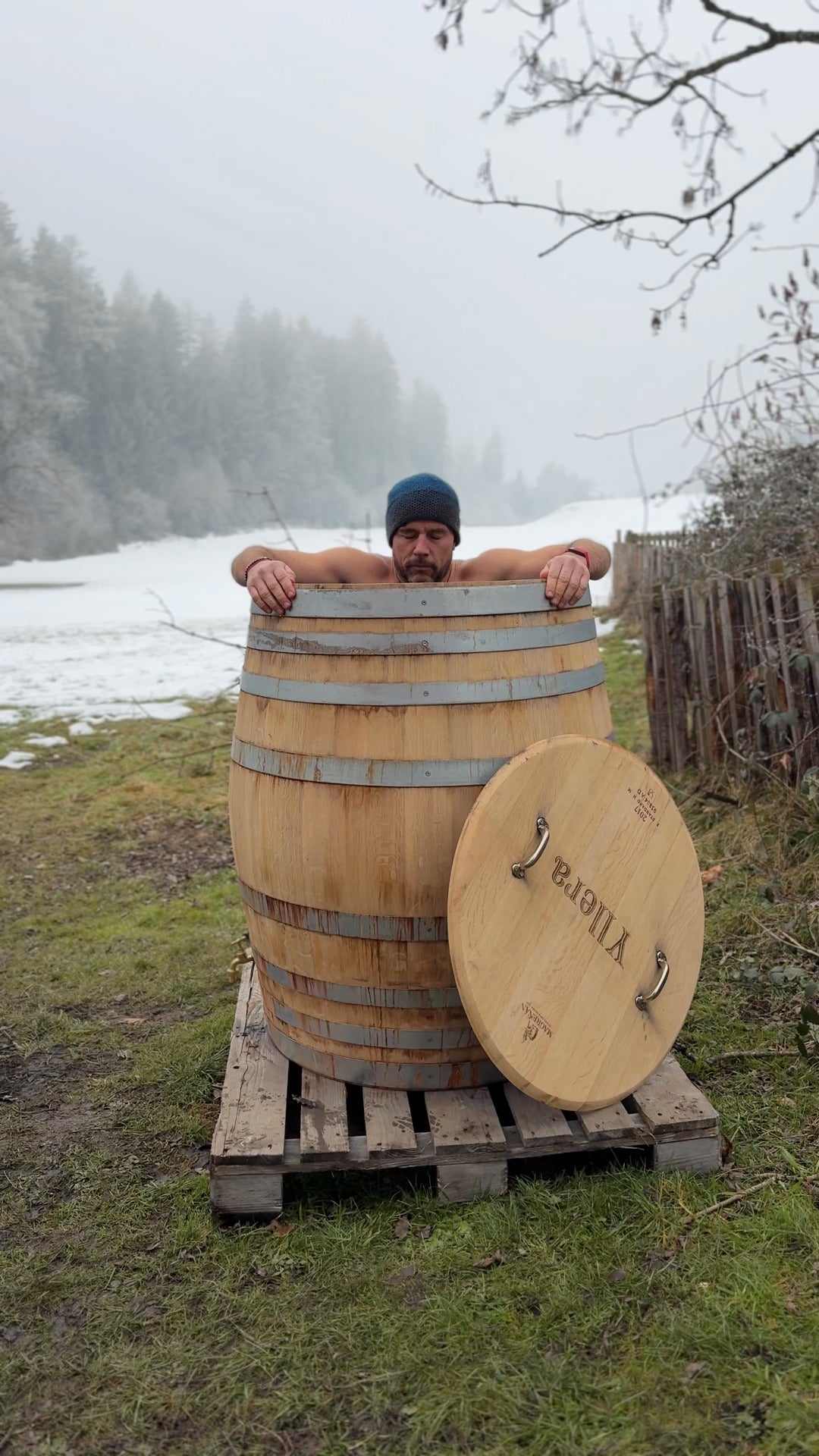 Mann beim Eisbaden in einem Eisbadefass aus einem gebrauchten Eichenweinfass im Winter